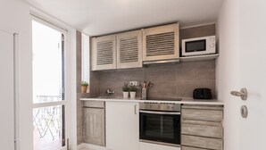 Una cocina compacta con microondas, horno y armarios.