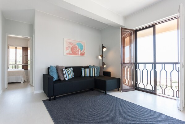 A modern living room with a black sectional sofa, a patterned rug, and a large window with a view.