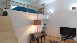 A modern living room with a staircase, a dining area, and a TV. - FLH Porto Stylish Apartment (Oporto)