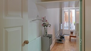 A narrow hallway with a wooden floor, a white door, and a small table with a vase of flowers. - FLH Porto Stylish Apartment (Oporto)