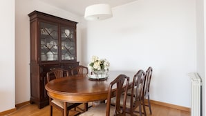 A dining room with a wooden table, six chairs, a cabinet, and a hanging light fixture.