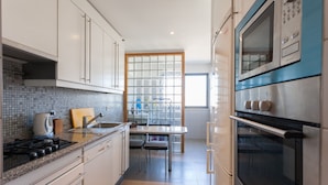 A modern kitchen with white cabinets, a tiled backsplash, a gas stove, a microwave, and an oven.