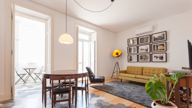 A living room with a dining area, a sofa, a coffee table, and a potted plant. - FLH Bica Modern Flat with View (Lisbon)