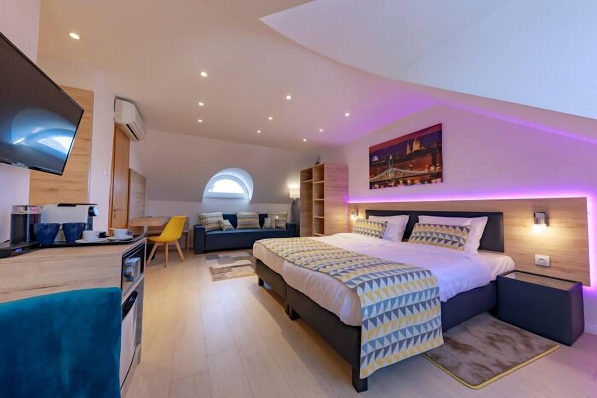 A modern bedroom with a large bed, a TV, a desk, and a chair.
