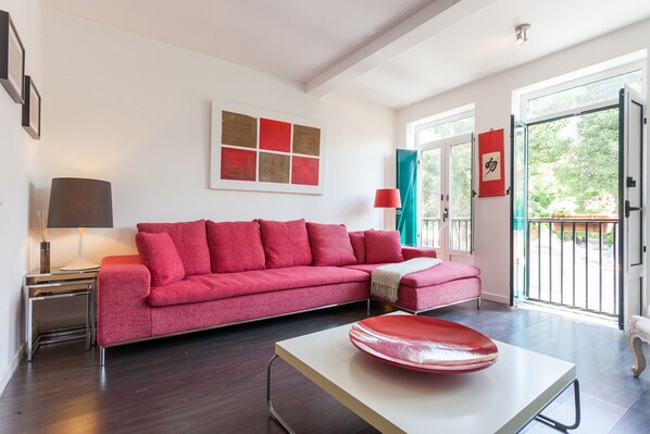 A modern living room with a red sofa, a white coffee table, and a painting on the wall.