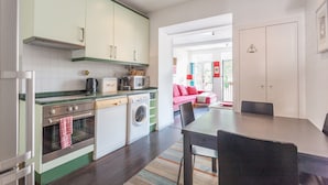A modern kitchen with a dining area, a washing machine, and a microwave. - FLH Príncipe Real Design Flat (Lisbon)