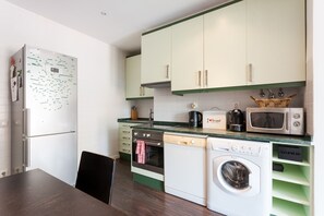 A kitchen with a refrigerator, oven, microwave, dishwasher, and washing machine.