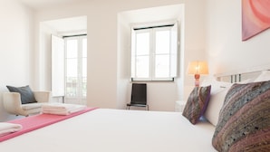 A hotel room with a bed, a chair, a table, and two windows. - FLH Príncipe Real Design Flat (Lisbon)