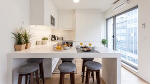 A modern kitchen with a central island, bar stools, and breakfast items.