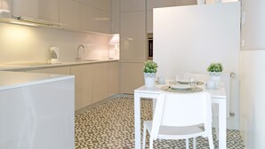 Een moderne keuken met witte kasten, een eettafel met stoelen en een vloer met patroon.