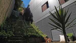 A modern building with a stone staircase, potted plants, and a tree. - FLH Luxury Porto River View (Vila Nova de Gaia)