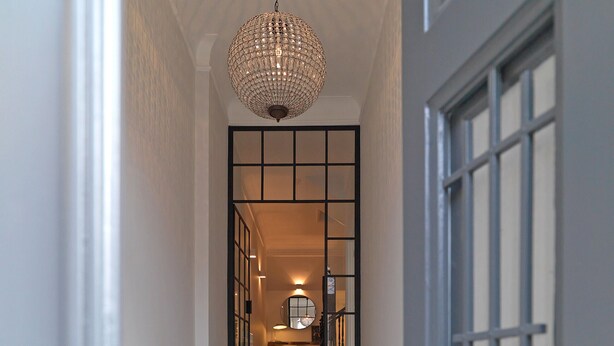 A staircase leading to a room with a chandelier, a door with a grid pattern, and a patterned floor. - FLH Seaside Luxury House in Porto (Oporto)