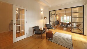 A spacious living room with wooden flooring, a large sliding glass door, and a dining area with a table and chairs. - FLH Seaside Luxury House in Porto (Oporto)