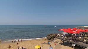 A beach with red umbrellas, a wooden walkway, and people relaxing. - FLH Seaside Luxury House in Porto (Oporto)