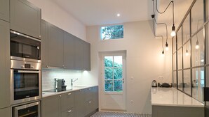 A modern kitchen with grey cabinets, stainless steel appliances, a patterned floor, and a large window. - FLH Seaside Luxury House in Porto (Oporto)