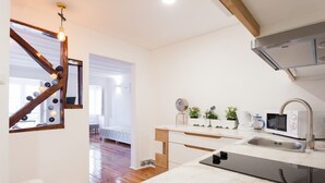 Cocina moderna con microondas integrado, lavamanos y una escalera de madera que conduce a otra habitación.