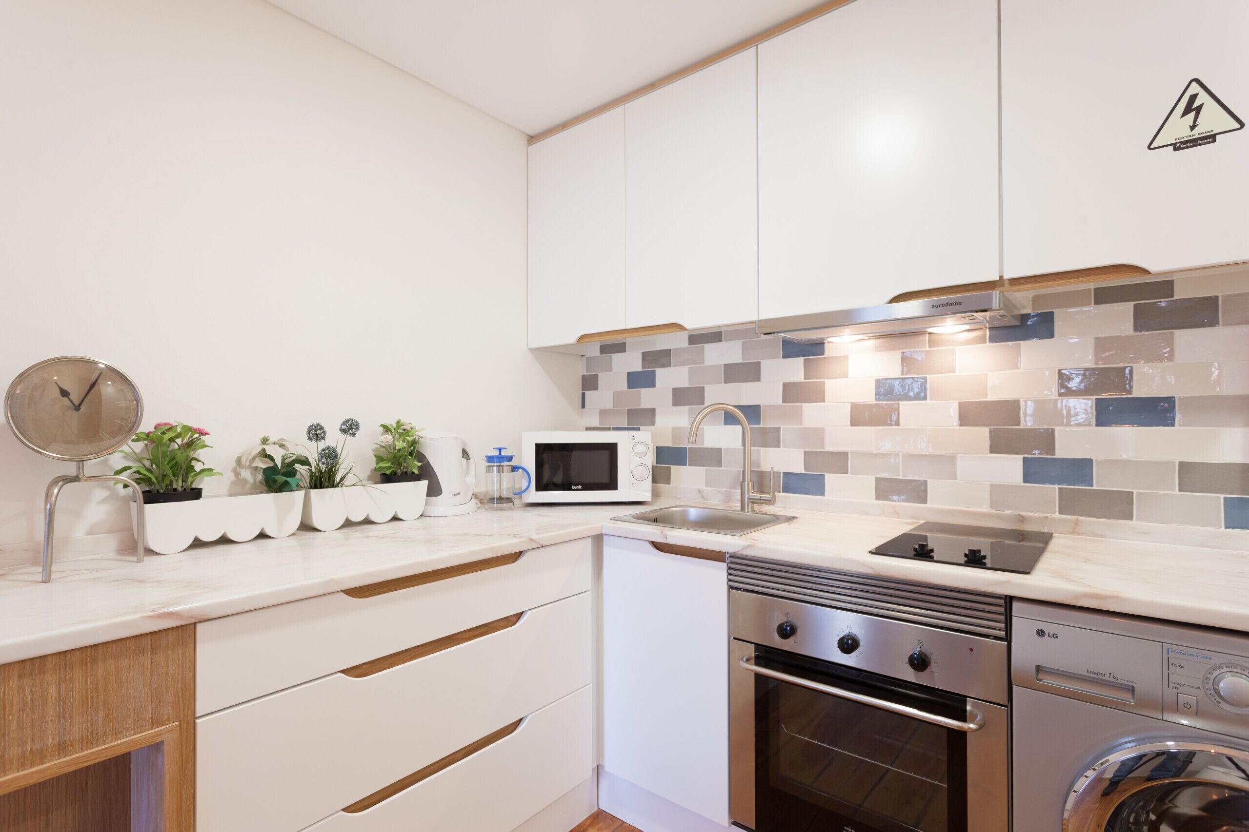 A modern kitchen with white cabinetry, a microwave, a sink, and a built-in oven.