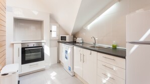 A modern kitchen with white cabinetry, a built-in oven, a microwave, a dishwasher, and a sink. - FLH Santa Marta Cozy Flat (Lisbon)