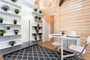 A modern room with a white table and chairs, a black and white patterned rug, and shelves with potted plants. - FLH Santa Marta Cozy Flat (Lisbon)