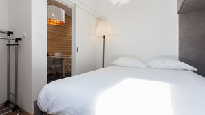 A neatly arranged hotel room with a bed, a desk, and a chair. - FLH Santa Marta Cozy Flat (Lisbon)