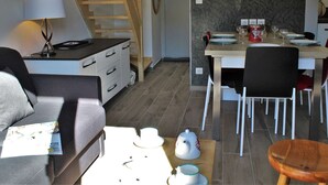 Un salon moderne comprenant un canapé, une table à manger pour deux personnes et un coin cuisine avec une cuisinière et des placards.