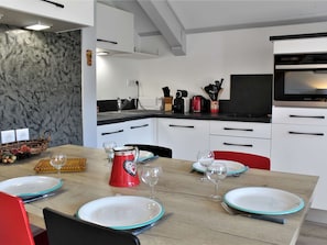Uma cozinha moderna com armários brancos, bancada preta e forno embutido.