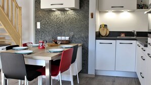 Une cuisine moderne avec des meubles blancs, une table à manger en bois et des chaises rouges.