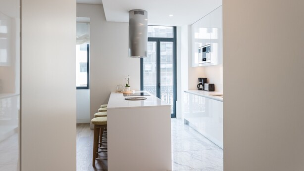 Eine moderne Küche mit Kochinsel, Barhocker und Kaffeemaschine.