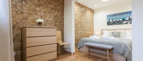 Ein Schlafzimmer mit Steinwand, Holzmöbeln, einem Bett mit gemustertem Überwurf und einem Gemälde an der Wand.