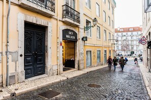 A cobblestone street with a building featuring a black ornate door and a sign reading "SKY WALKER".