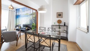 Una sala de estar moderna con una mesa de comedor de vidrio, un sofá y un ventanal con vista al mar.