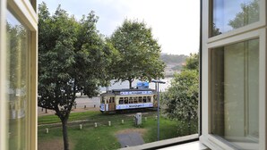 A view of a tram with "E. C. Porto" written on it, passing by a tree and a body of water. - FLH Oporto Captain House - Calem Apartment (Oporto)