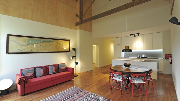 A cozy living area with a red sofa, a dining table with red chairs, and a kitchen in the background. - FLH Oporto Captain House - Calem Apartment (Oporto)