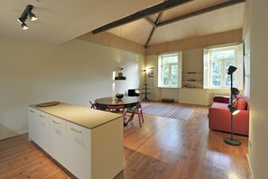 A spacious living area with a wooden floor, a round dining table, and a sofa.