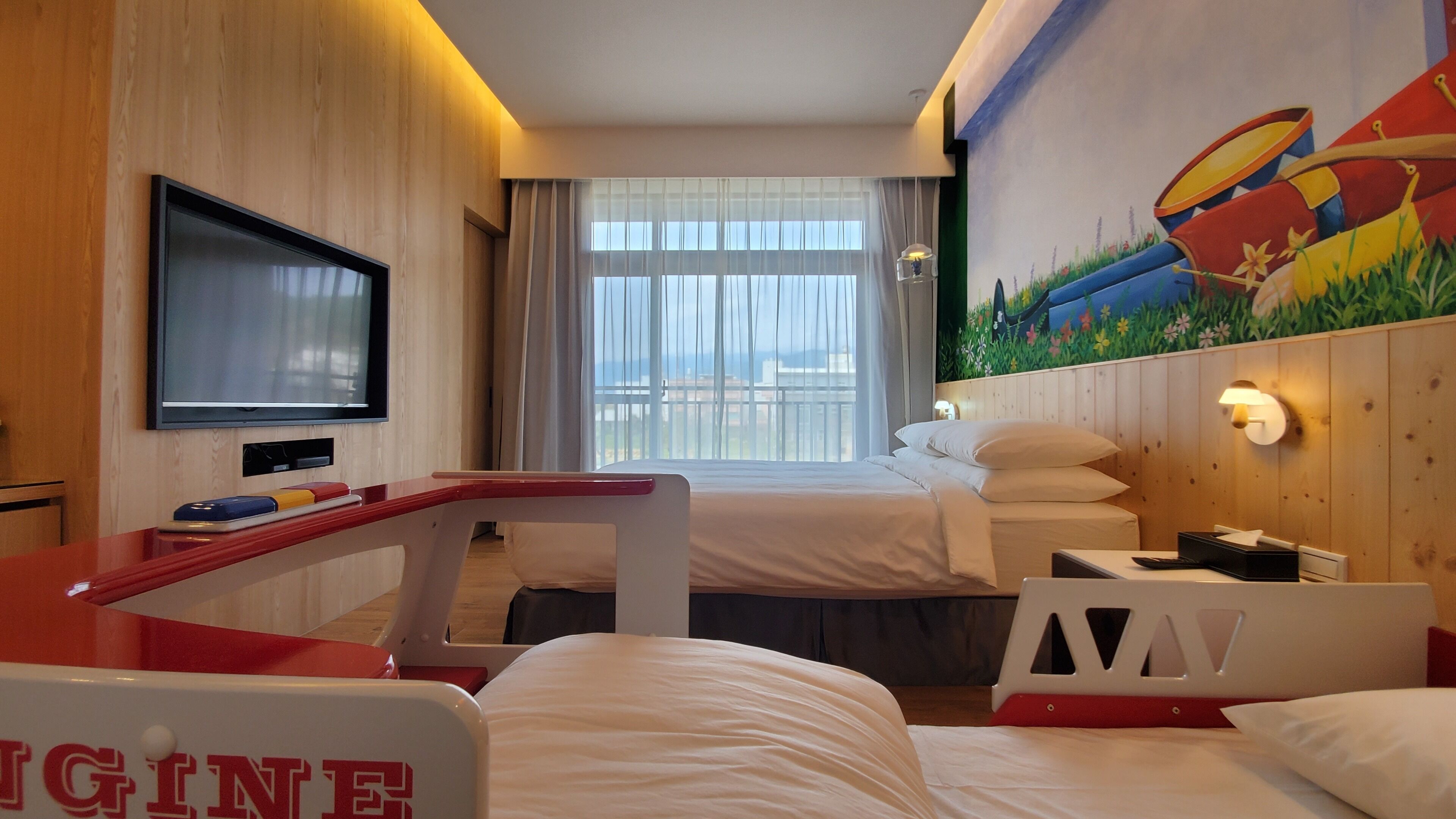 Una habitación de hotel con cama, televisión, escritorio y un cuadro en la pared.