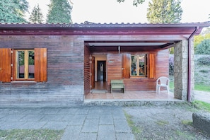 A wooden cabin with a porch, a door, and a small table. - HI Geres- Pousada da Juventude - Hostel (Terras de Bouro)