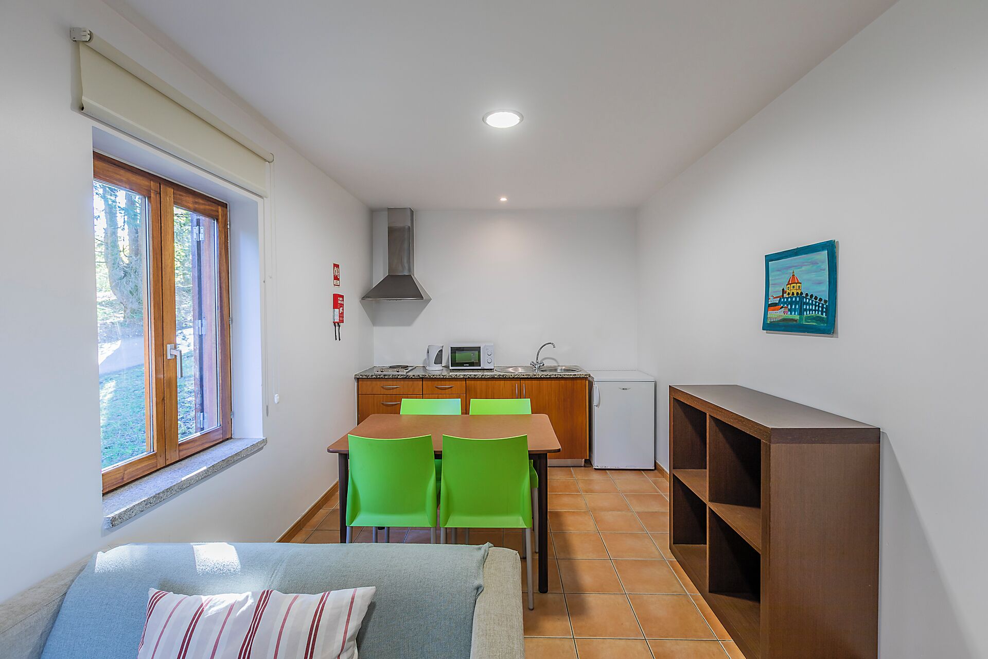 A compact kitchen with a dining area, a built-in microwave, and a single chair.