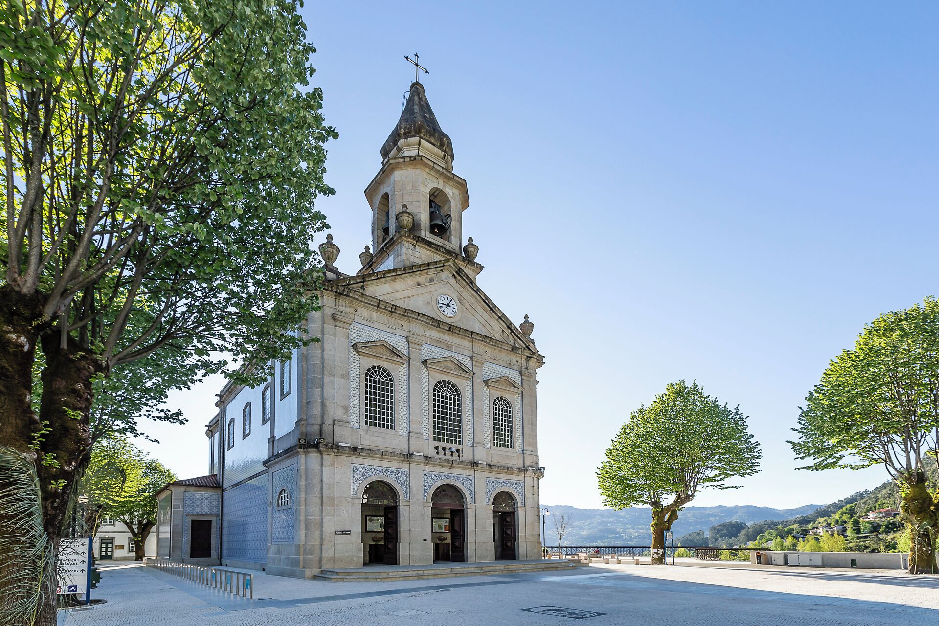 Una iglesia histórica con un campanario, ventanas de arco y fachada de tejas.