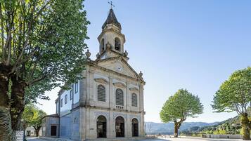 Una iglesia histórica con un campanario, ventanas de arco y fachada de tejas.
