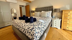 Ein Schlafzimmer mit Bett, Nachttischen, einem Kleiderschrank und einem Spiegel.