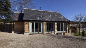 Eine Blockhütte mit geneigtem Dach, großen Fenstern und einem Schornstein.