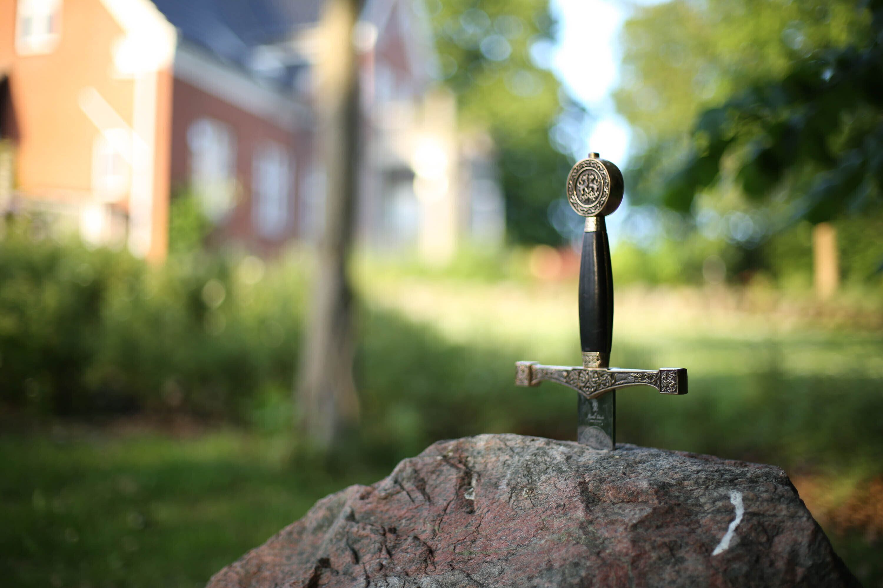A sword with a decorative hilt on a rock.