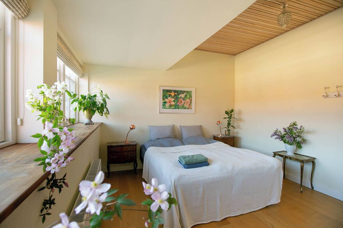A bedroom with a bed, two bedside tables, a window with curtains, and a ceiling fan.