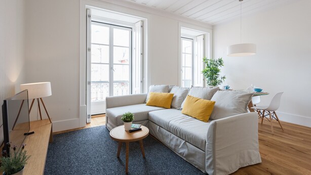 Una sala de estar moderna con un sofá, una mesita redonda y una lámpara.