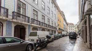 A narrow street lined with colorful buildings, parked cars, and a motorcycle. - FLH Baixa Cozy Apartment II (Lisbon)