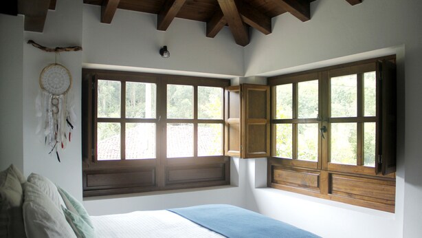 Une chambre avec un grand lit, un attrape-rêves et une vue par la fenêtre.