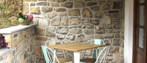 A stone wall with a wooden table and two chairs.