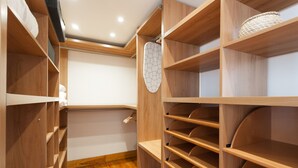 A wooden closet with multiple shelves and hanging space, featuring a woven basket on one shelf. - FLH Alfama River View Flat (Lisbon)
