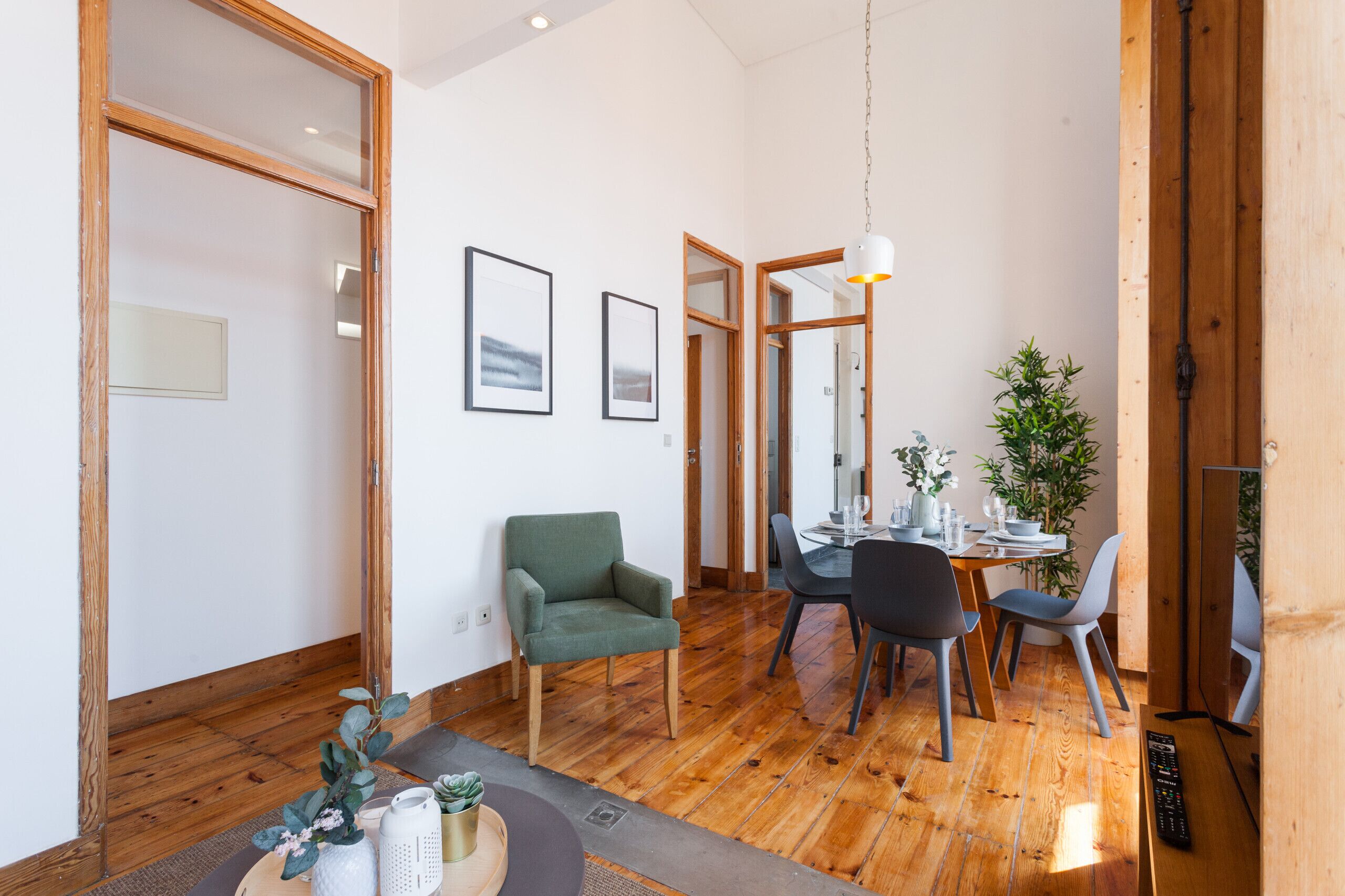 Un espace repas moderne avec un plancher en bois, un fauteuil vert et une table à manger avec des chaises.