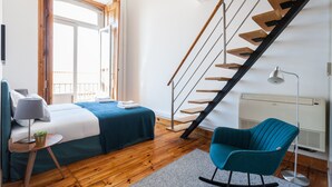 A bedroom with a bed, a chair, a desk, a lamp, and a staircase. - FLH Alfama River View Flat (Lisbon)